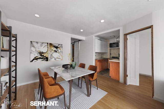 165 Christopher St Unit 2K, New York City, NY 10014 - dining room with a barn door, light wood-style floors, recessed lighting, and baseboards