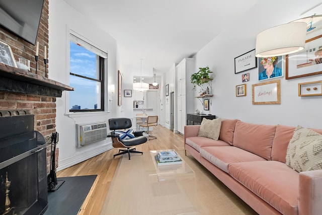 252 W 20th St Unit 3B, New York City, NY 10011 - living room featuring light wood-style floors, an AC wall unit, and a brick fireplace