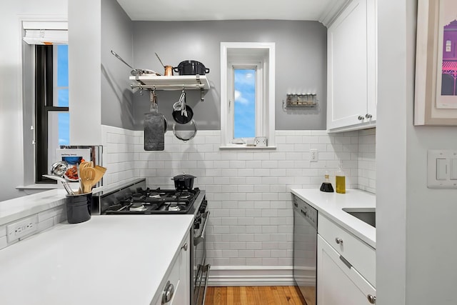 kitchen with stainless steel appliances, open shelves, white cabinetry, light countertops, and wood finished floors