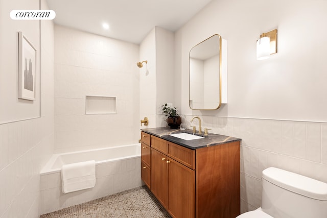 bathroom featuring tiled shower / bath combo, vanity, wainscoting, and toilet