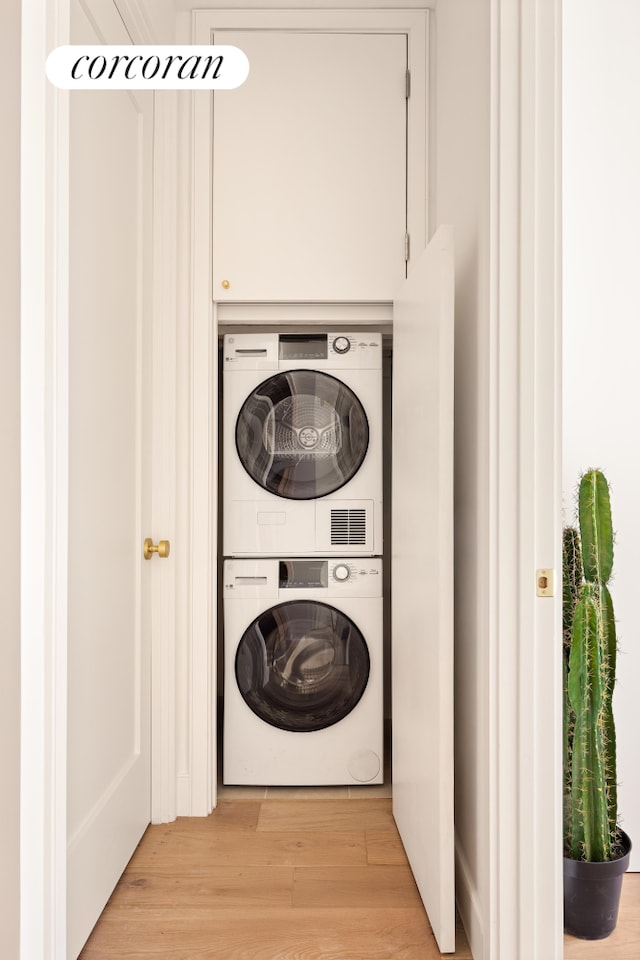 laundry room featuring laundry area, stacked washer and clothes dryer, and light wood finished floors