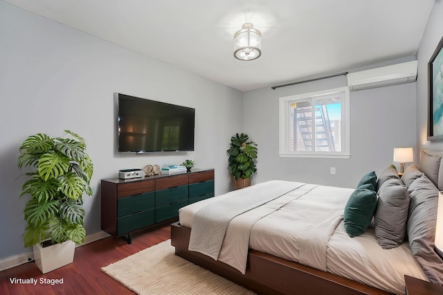 bedroom featuring a wall mounted air conditioner, dark wood-style flooring, and baseboards