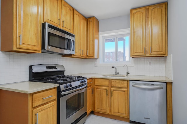 kitchen with stainless steel appliances, a sink, backsplash, and brown cabinets