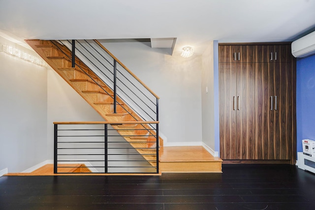 stairs featuring hardwood / wood-style floors, a wall mounted air conditioner, and baseboards