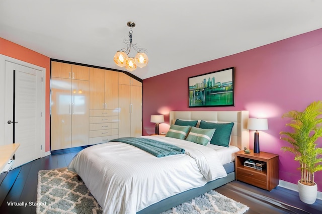 bedroom with wood finished floors, a chandelier, baseboards, and a closet