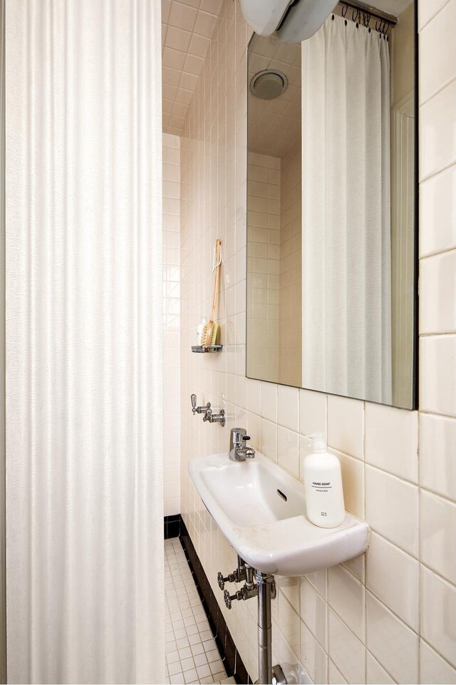 bathroom featuring a sink, tile walls, tile patterned flooring, and backsplash