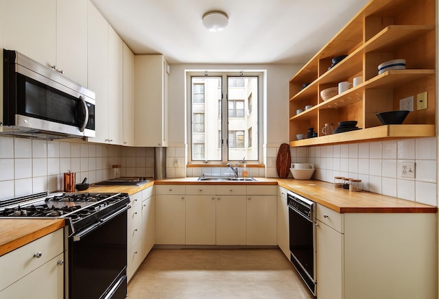 kitchen featuring butcher block countertops, a sink, decorative backsplash, and black appliances