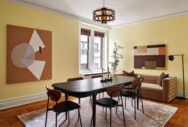 dining area featuring baseboards, ornamental molding, and a notable chandelier