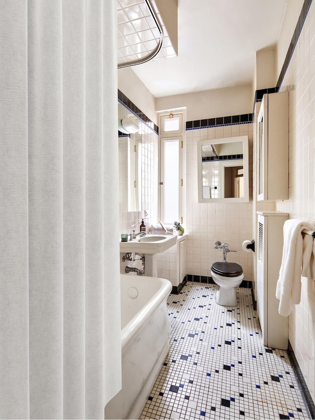 full bathroom with tile patterned flooring, a bath, and tile walls