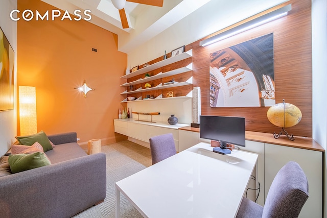 office area featuring baseboards, a ceiling fan, and a high ceiling