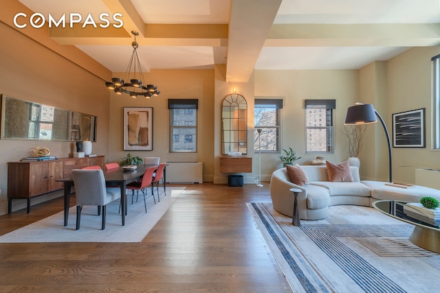 living area featuring beamed ceiling, baseboards, an inviting chandelier, and wood finished floors