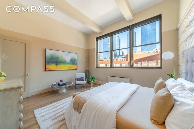 bedroom featuring baseboards, beamed ceiling, multiple windows, and wood finished floors
