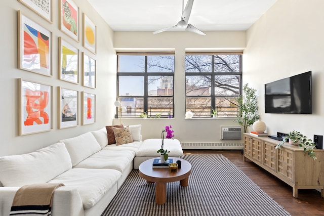 living room featuring dark wood-style floors, baseboard heating, a ceiling fan, and plenty of natural light