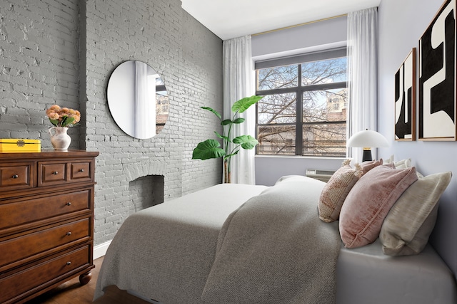 bedroom featuring dark wood-style flooring and brick wall