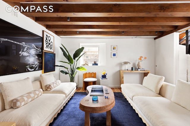 living area featuring baseboards and beam ceiling