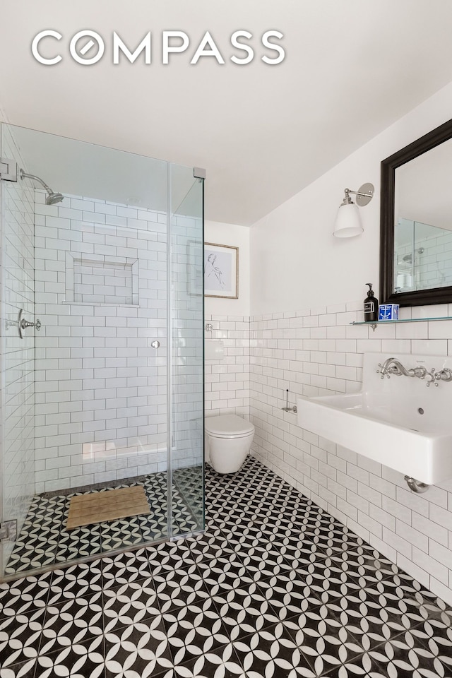 bathroom featuring wainscoting, a stall shower, toilet, and tile walls