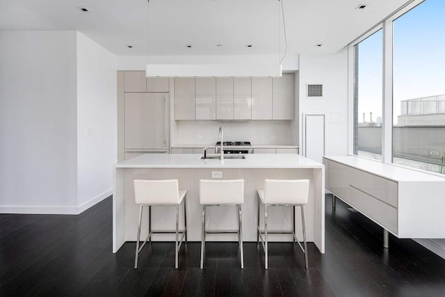 kitchen with visible vents, modern cabinets, dark wood finished floors, a sink, and paneled fridge