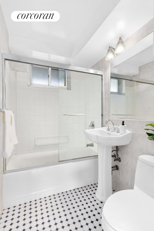 185 Park Row Unit 17F, New York City, NY 10038 - full bathroom featuring toilet, bath / shower combo with glass door, and tile walls