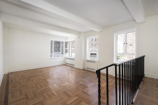 spare room with baseboards, radiator heating unit, and beam ceiling