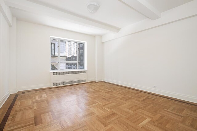 unfurnished room with radiator, beamed ceiling, and baseboards
