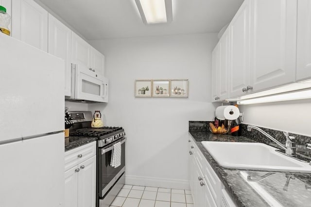 404 E 76th St Unit 4-O, New York City, NY 10021 - kitchen with white appliances, a sink, light tile patterned flooring, white cabinetry, and baseboards