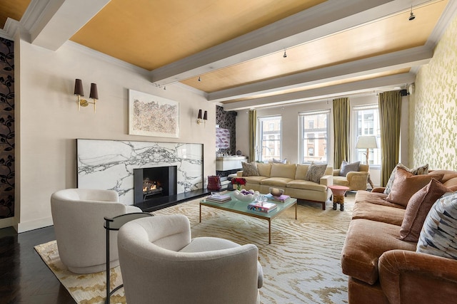 living room featuring beamed ceiling, baseboards, ornamental molding, a fireplace, and wood finished floors
