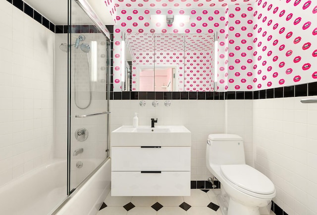 full bathroom featuring toilet, tile walls, enclosed tub / shower combo, and vanity