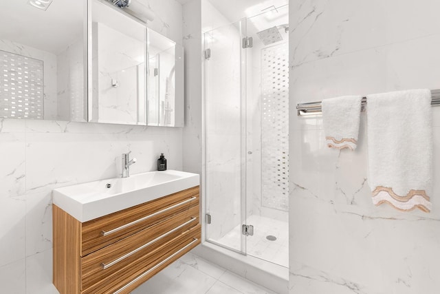 full bath with a marble finish shower, marble finish floor, tile walls, and vanity