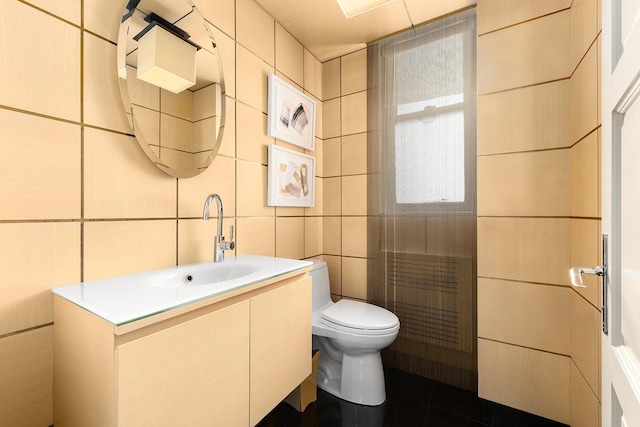 bathroom featuring tile patterned floors, vanity, toilet, and tile walls