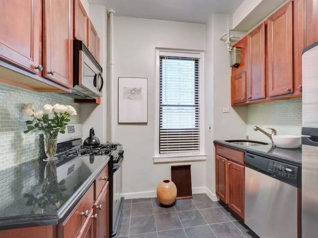 120 W 58th St Unit 7B, New York City, NY 10019 - kitchen with appliances with stainless steel finishes, decorative backsplash, dark tile patterned floors, baseboards, and a sink
