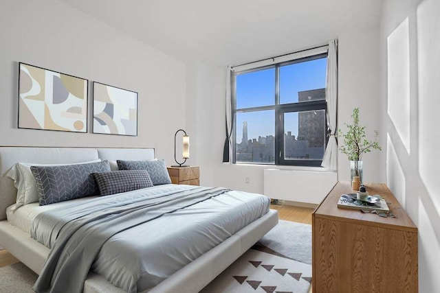 bedroom featuring a city view and wood finished floors