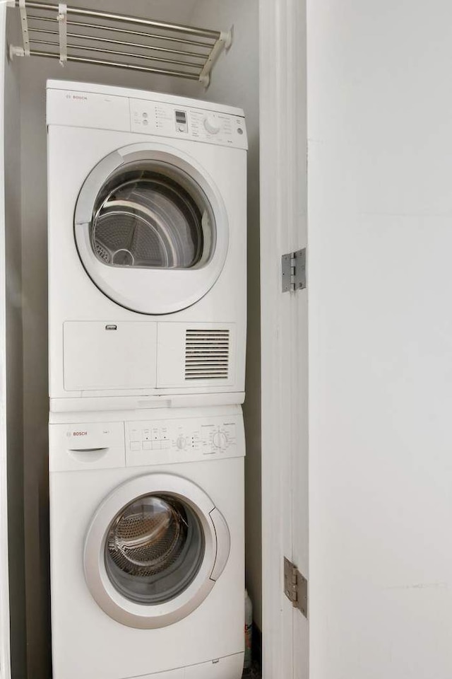 clothes washing area with stacked washer and dryer and laundry area