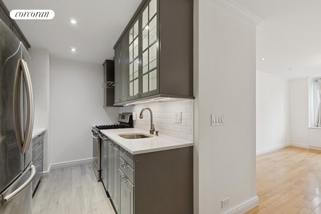 61 W 62nd St Unit 27G, New York City, NY 10023 - kitchen featuring stainless steel appliances, gray cabinetry, a sink, light wood-type flooring, and backsplash