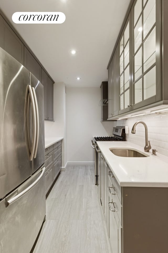 61 W 62nd St Unit 27G, New York City, NY 10023 - kitchen with appliances with stainless steel finishes, glass insert cabinets, gray cabinets, decorative backsplash, and a sink