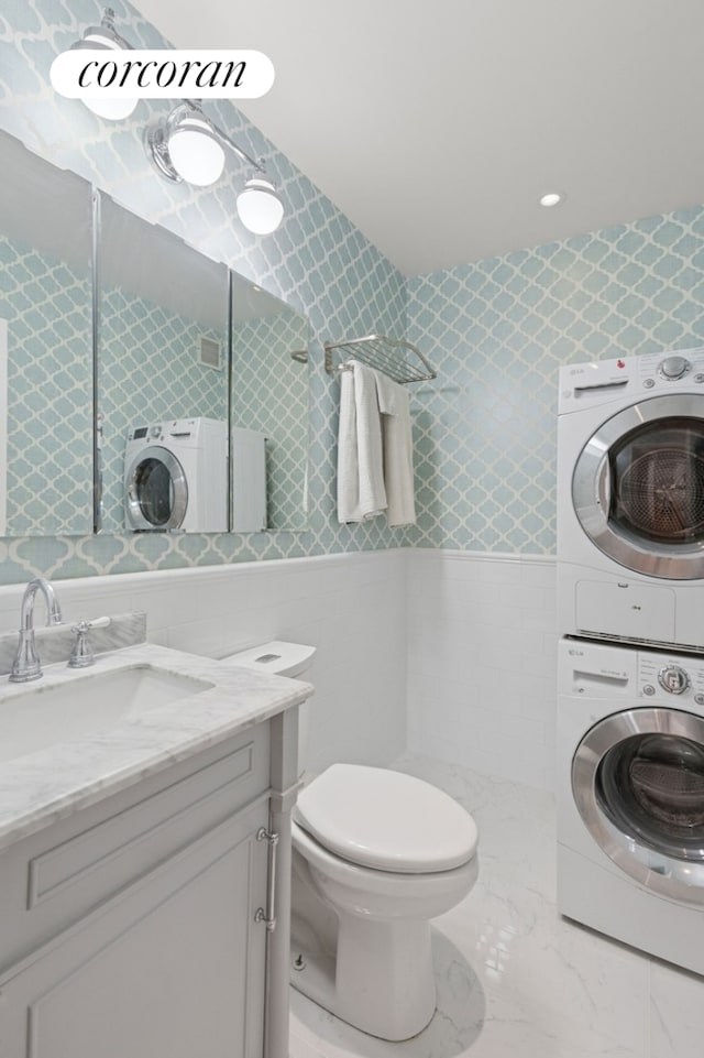 61 W 62nd St Unit 27G, New York City, NY 10023 - bathroom featuring stacked washer and clothes dryer, tile walls, vanity, toilet, and tiled shower