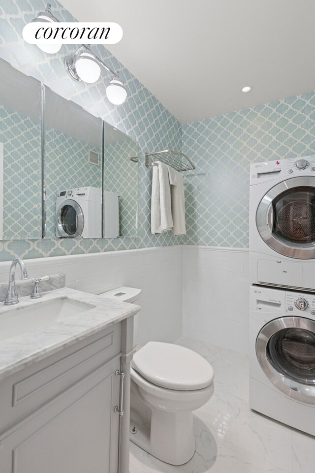 61 W 62nd St Unit 27G, New York City, NY 10023 - bathroom with stacked washer / drying machine, tile walls, vanity, toilet, and tiled shower