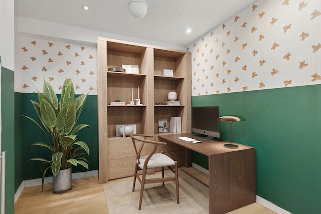 home office featuring baseboards, wallpapered walls, wood finished floors, and built in features