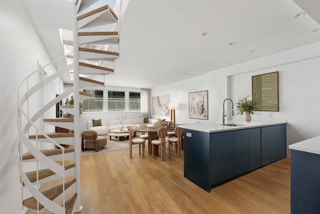 interior space featuring modern cabinets, a sink, light wood-type flooring, light countertops, and dark cabinets