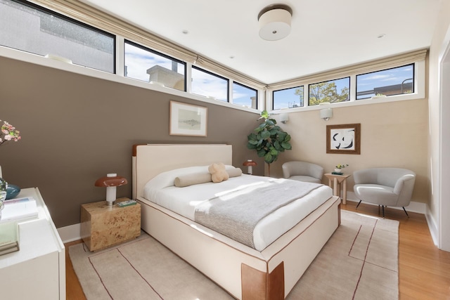 bedroom with light wood-style floors, baseboards, and multiple windows