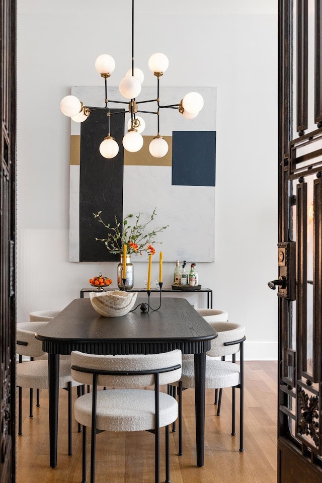 dining space featuring light wood-style flooring, a chandelier, and baseboards