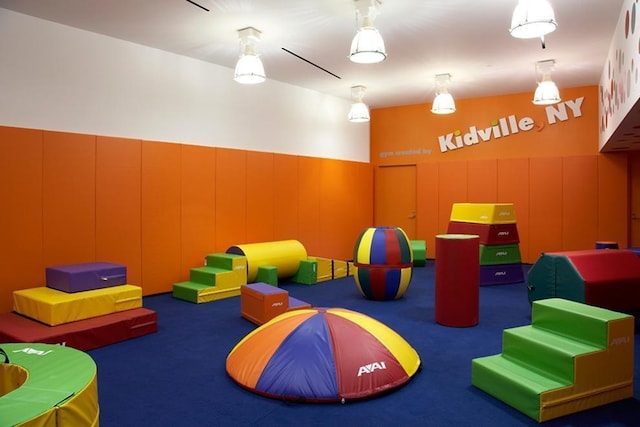 playroom with carpet, a decorative wall, and a wainscoted wall