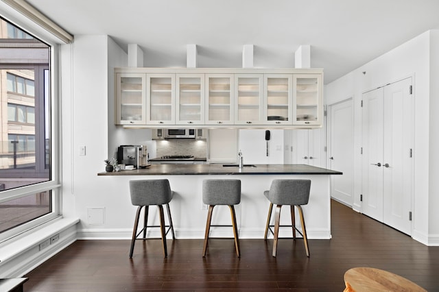 kitchen with stainless steel microwave, dark countertops, a sink, and a kitchen bar