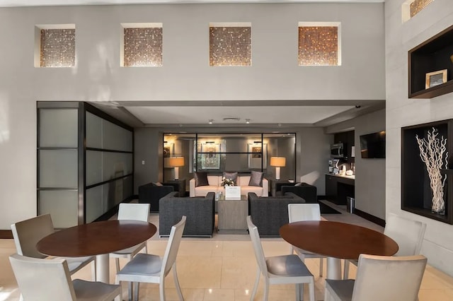 dining space with a high ceiling and light tile patterned flooring