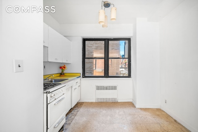 kitchen featuring white range with gas stovetop, radiator heating unit, light countertops, white cabinetry, and a sink