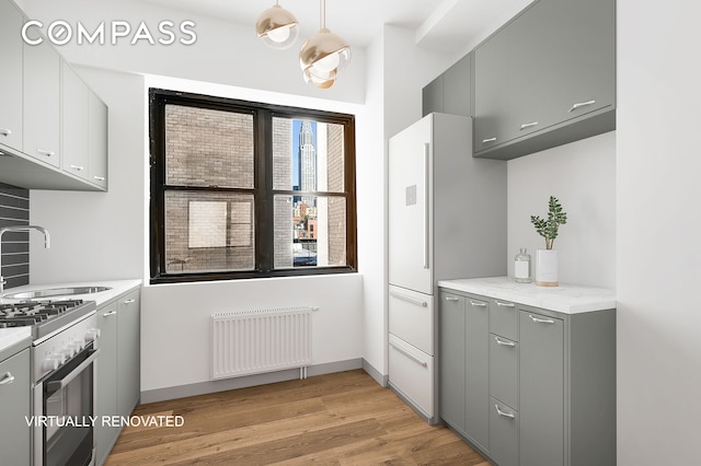 7 Park Ave Unit 66, New York City, NY 10016 - kitchen with radiator heating unit, a sink, gray cabinetry, and light wood finished floors