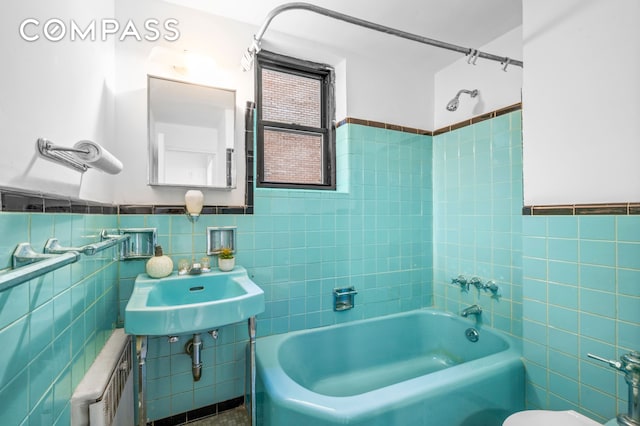 full bath featuring radiator heating unit, tile walls, bathtub / shower combination, and a sink