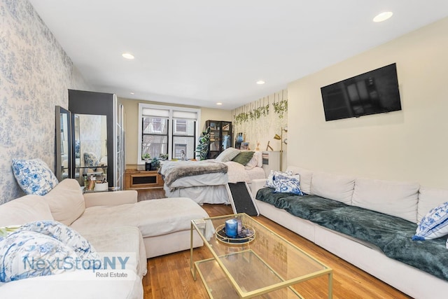 bedroom featuring wood finished floors, recessed lighting, and wallpapered walls
