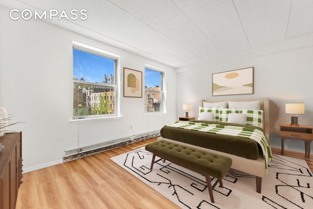 bedroom featuring a baseboard radiator, wood finished floors, and baseboards
