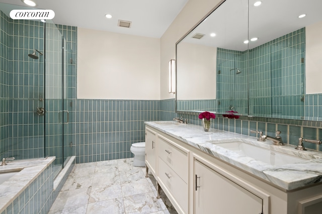 bathroom with visible vents, toilet, tile walls, a shower stall, and a sink