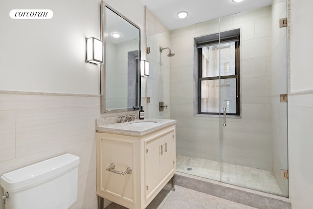full bathroom with tile walls, tile patterned flooring, a shower stall, vanity, and toilet